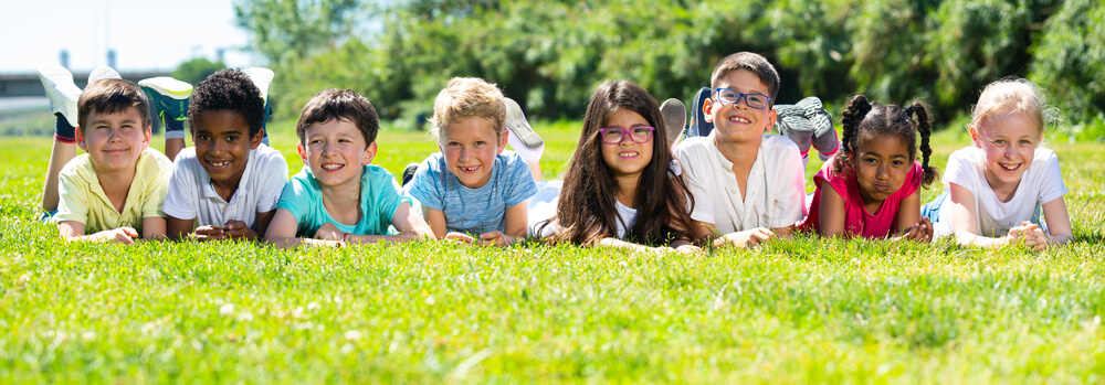 Children laying down in a sunny grassy field.