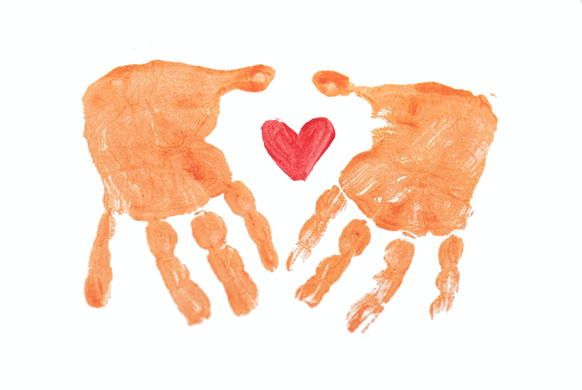 Two painted hands upside down, with a painted red heart in between.